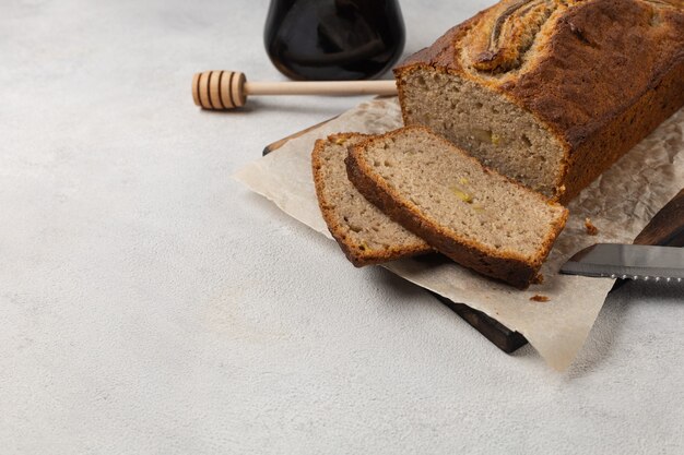 Geschnittenes fertiges Bananenbrot mit Honig auf weißem Teller