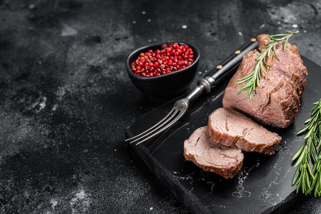 Geschnittenes Filetsteak Roastbeef auf Marmorplatte mit Rosmarin Schwarzer Hintergrund Draufsicht Kopierbereich