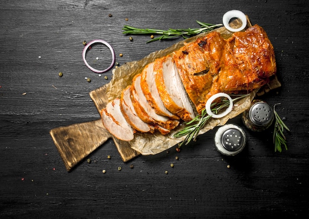 Geschnittenes gegrilltes Fleisch auf einem Brett mit Gewürzen.