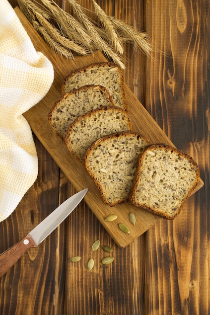 Geschnittenes hausgemachtes Brot auf dem Schneidebrett auf dem braunen hölzernen Hintergrund. Draufsicht. Lage vertikal.