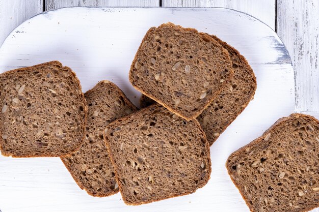 Geschnittenes hausgemachtes Brot auf weißem Holztisch. Ansicht von oben.