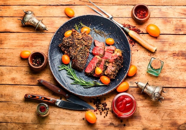 Geschnittenes Rindersteak gebraten mit Kumquat, Rosmarin und Gewürzen. Kalbsentrecôte auf einem Teller