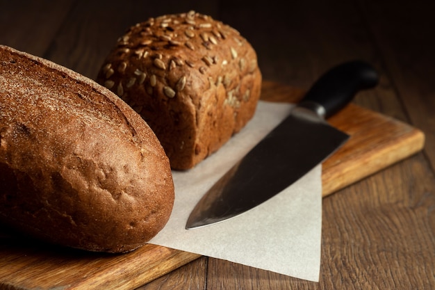 Geschnittenes Roggenbrot und eine Messernahaufnahme, auf einem hölzernen Schneidebrett