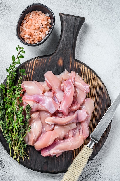 Geschnittenes rohes Hähnchenbrustfilet auf einem Holzbrett. Weißer Hintergrund. Ansicht von oben.