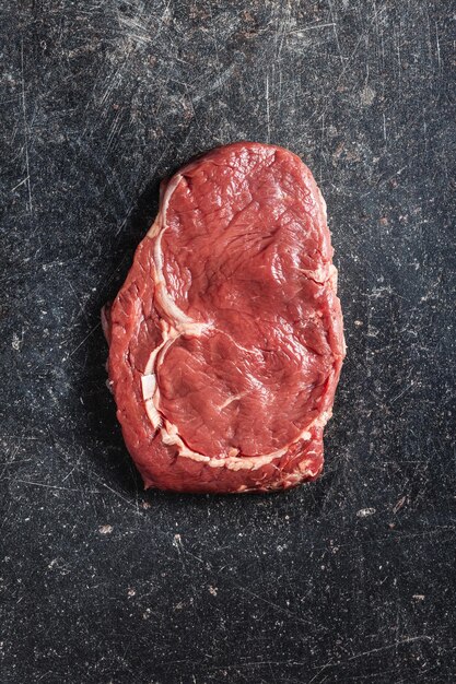 Geschnittenes rohes Ribeye-Steak auf einem schwarzen Küchentisch von oben
