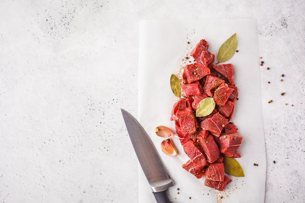 Geschnittenes rohes Rindfleisch mit Gewürzen auf einem weißen Hintergrund, Draufsicht.