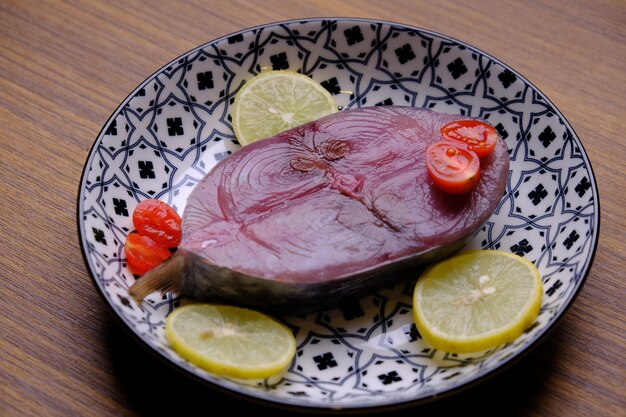 geschnittenes Thunfischsteak. rohes Thunfischsteak in einer Keramikschale. Zitronenschnitze, Kirschtomaten. Protein Tier.