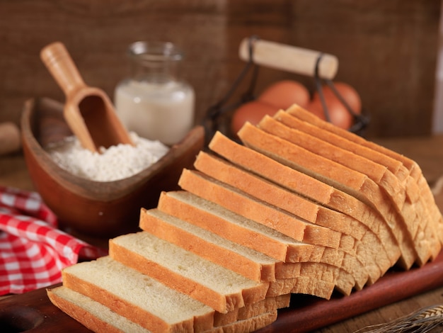 Geschnittenes Toastbrot Weißbrot (Shokupan oder Roti Tawar) zum Frühstück auf Holzuntergrund, serviert mit Ei und Milch. Bäckereikonzept Bild