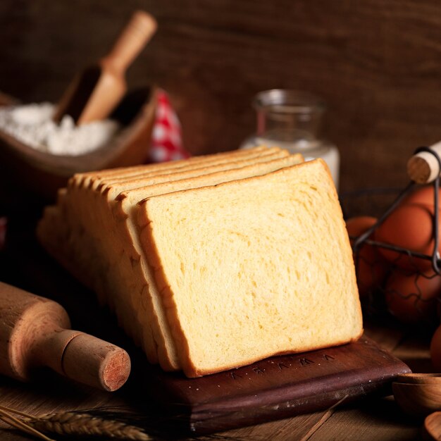 Geschnittenes Toastbrot Weißbrot (Shokupan oder Roti Tawar) zum Frühstück auf Holzuntergrund, serviert mit Ei und Milch. Bäckereikonzept Bild