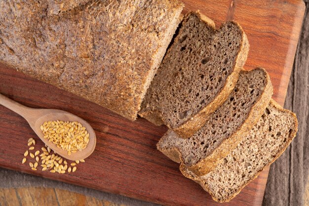 Geschnittenes Vollkornbrot mit goldenem Leinsamen über Holzbrett.