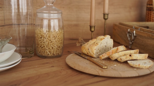 Geschnittenes weißbrot auf einem holztablett. moderne küche im skandinavischen stil. nudeln im glas