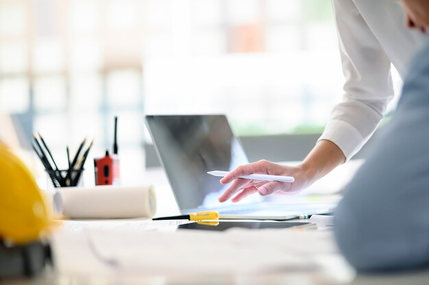 Geschossen von der weiblichen Hand, die Stift hält und für neues Projekt mit ihrem Team im Büro arbeitet