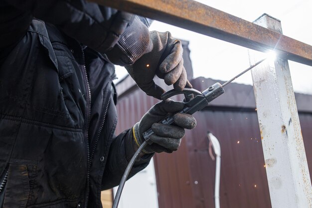 Foto geschütztes metallbogenschweißen arbeiter schweißen metall mit elektroden, tragen schutzhelm und handschuhe nahaufnahme von elektrodenschweißen und elektrischen funken