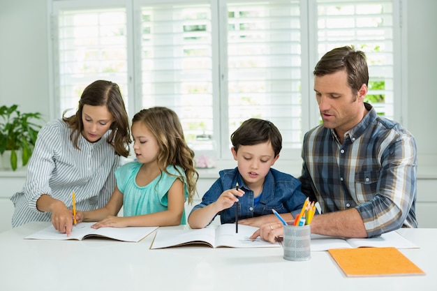 Geschwister bekommen Hilfe bei den Hausaufgaben von den Eltern