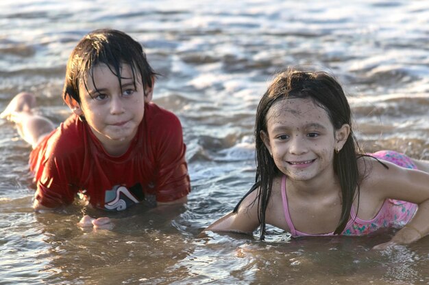 Foto geschwister, die im meer liegen und wegschauen