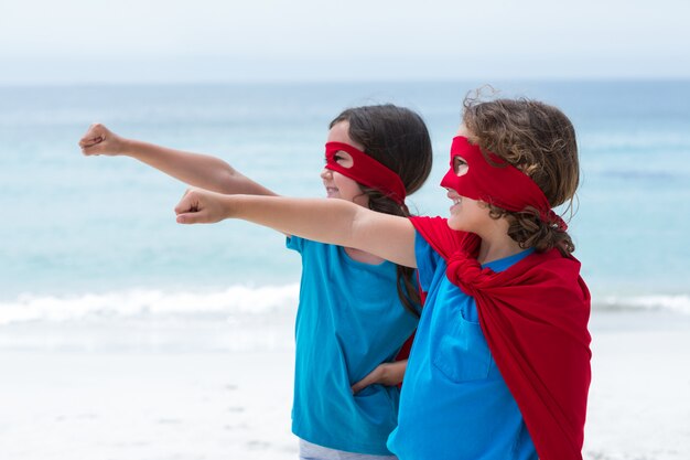 Geschwister im Superheldkostüm am Strand