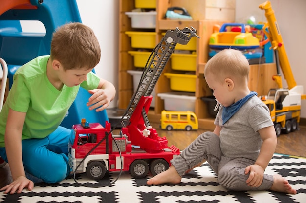 Geschwister Jungen spielen mit einem Spielzeug-Feuerwehrauto im Kinderzimmer Kinder spielen Autos in ihrem Zimmer