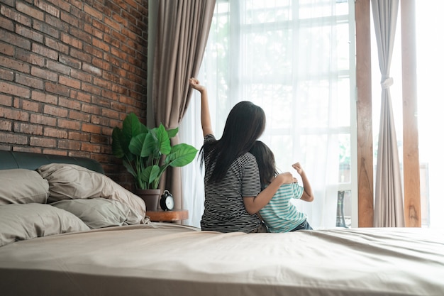 Geschwister sitzen auf dem Bett und schauen zum Fenster