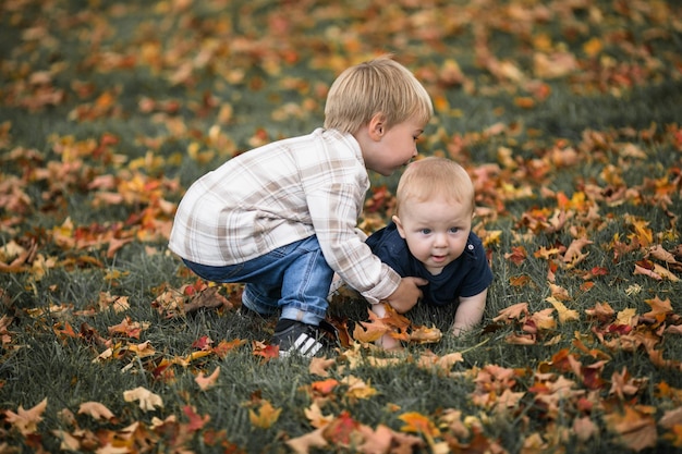 Geschwisterkinder spielen im grünen Park Familienspaß und Freude auf dem Spielplatz Aktiver Sohn kriecht barfuß