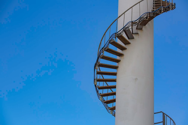 Geschwungene Treppe des Grundöllagertanks in der Erdölfabrik mit blauem Himmel Industrielle Erdölanlage Grundöl für Kfz-Motorenöl und Industrie