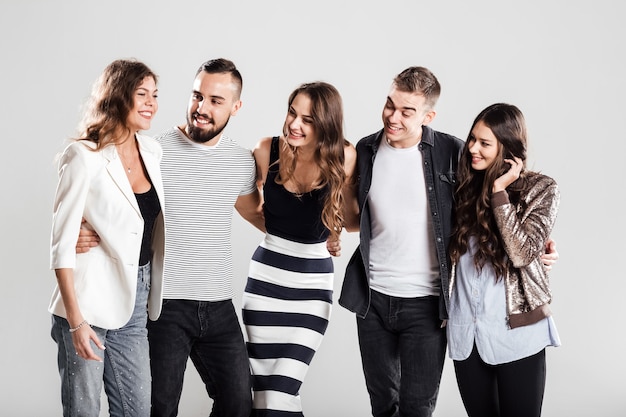 Gesellschaft von Mädchen und Jungs in modischer Freizeitkleidung sprechen auf weißem Hintergrund im Studio.