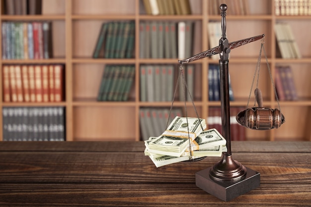 Gesetzliche Skalen und Geld auf Tabellenhintergrund. Symbol der Gerechtigkeit