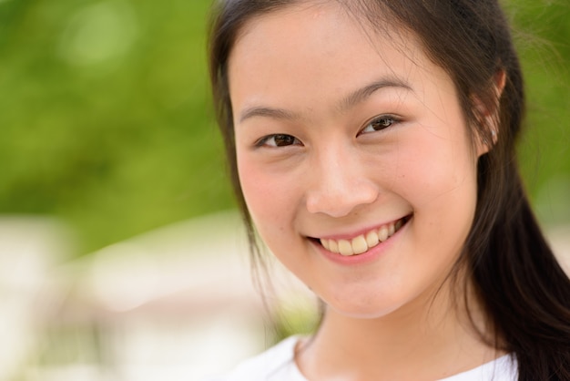 Gesicht der glücklichen jungen schönen asiatischen Frau, die draußen lächelt