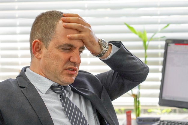 Gesicht der verärgerten Büroangestellten, Manager Mann in Stress vor dem Monitor des Computers