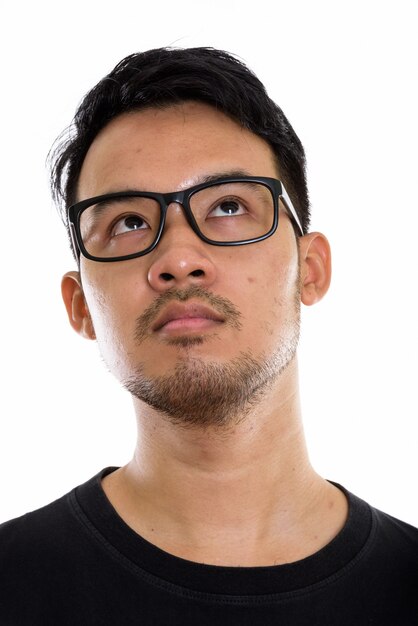 Gesicht des jungen asiatischen Mannes, der beim Aufschauen und Tragen der Brille denkt
