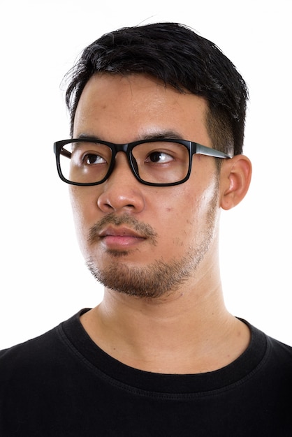 Gesicht des jungen asiatischen Mannes, der beim Betrachten der Entfernung und beim Tragen der Brille denkt