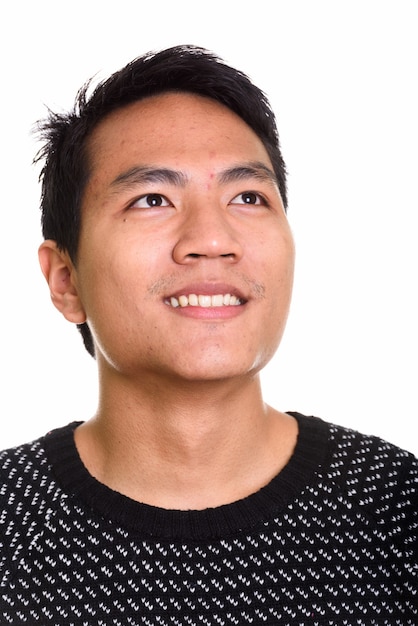 Gesicht des jungen glücklichen asiatischen Mannes lächelnd beim Denken
