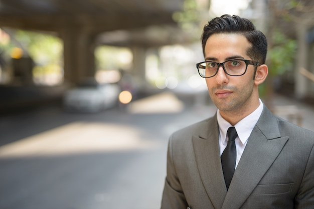 Gesicht des jungen gutaussehenden persischen Geschäftsmannes in den Stadtstraßen draußen