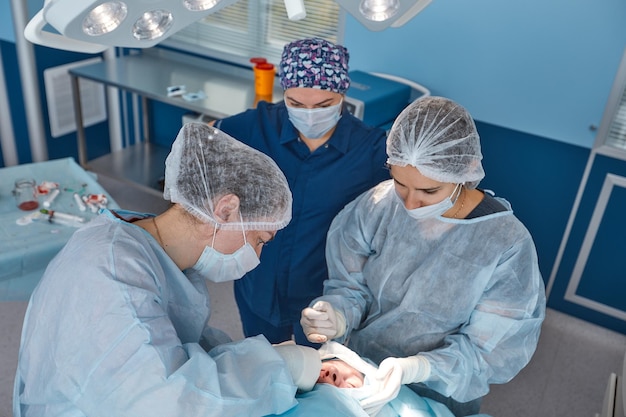 Gesicht eines Patienten, der sich einer Blepharoplastik unterzieht Der Chirurg schneidet das Augenlid und führt Manipulationen mit medizinischen Instrumenten durch