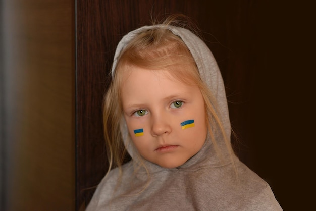 Gesicht eines ukrainischen Mädchens mit einer gemalten Flagge auf ihrer Wange Beten Sie für die Ukraine
