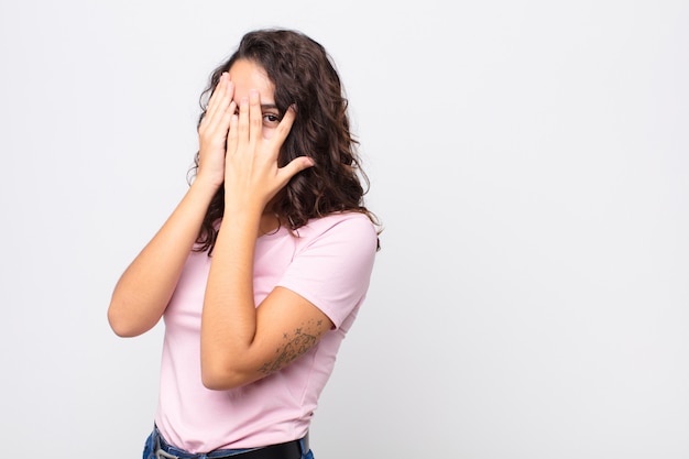 Gesicht mit den Händen bedecken, mit überraschtem Ausdruck zwischen die Finger spähen und zur Seite schauen