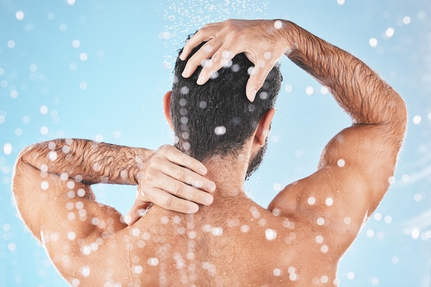 Gesicht zurück und Wasserspritzer des Mannes in der Dusche im Studio auf blauem Hintergrund Wassertropfen Dermatologie und männliches Model waschen, reinigen oder baden für frische Hygiene, Hautpflege, Wellness oder gesunde Haut