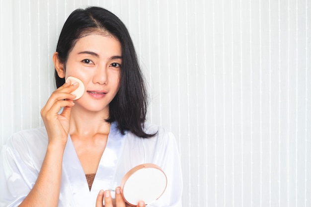 Gesichts Make-up. Schöne asiatische Frau, die Puder auf Gesicht aufträgt