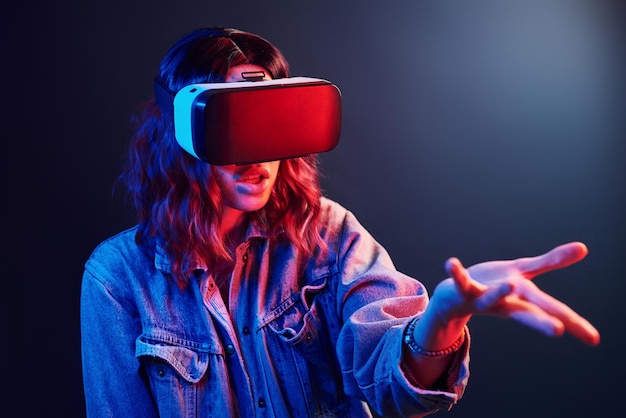 Gesichtsausdruck eines jungen Mädchens mit Virtual-Reality-Brille auf dem Kopf in rotem und blauem Neon im Studio