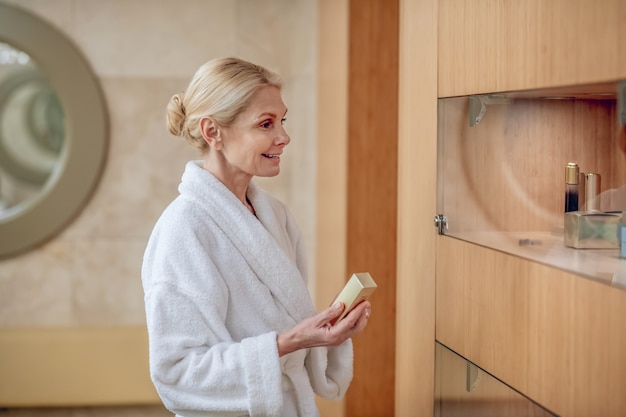 Gesichtscreme. Eine Frau in einem weißen Gewand, die in einem Schönheitszentrum Gesichtscreme wählt