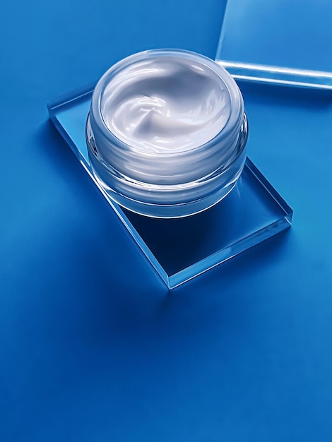 Gesichtscreme-Feuchtigkeitscreme-Glas auf Glas und blauem Hintergrund Schönheitsprodukt und Hautpflege-Kosmetikwissenschaft