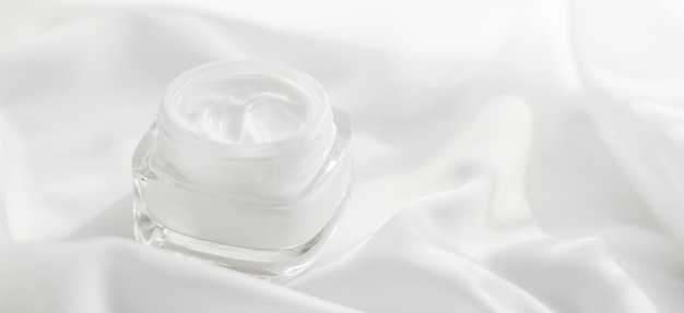 Gesichtscreme-Feuchtigkeitscremeglas auf Seidenhintergrund, feuchtigkeitsspendende Hautpflegelotion und Lifting-Emulsion, Antiage-Kosmetik für Luxus-Beauty-Hautpflegemarke