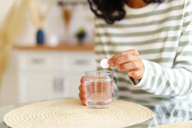 Foto gesichtslose ethnische weibliche abwaschpille mit einem glas wasser gesunde ergänzung heilmittel behandlung