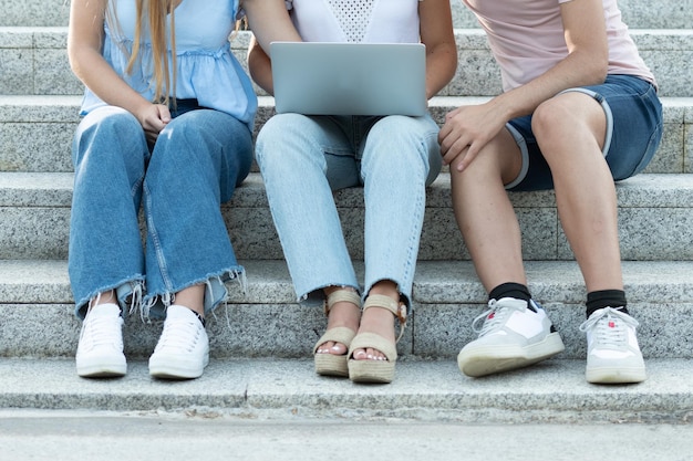 Gesichtslose Studenten, die auf Treppen sitzen und an einem Laptop arbeiten Teamarbeit im Jugendkonzept