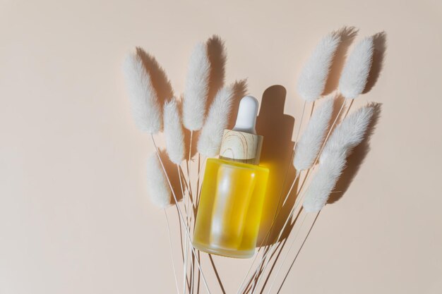 Foto gesichtsöl-kosmetikflasche auf beigefarbenem pastellhintergrund und getrocknete blumen mit schatten produktpräsentation draufsicht kopierbereich verpackung ohne marke