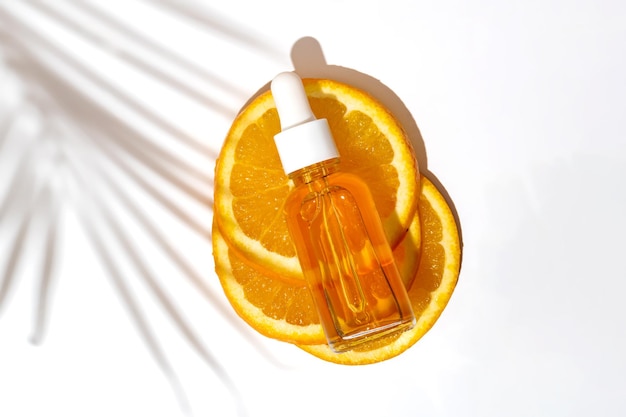 Gesichtsöl-Tropferflasche mit Vitamin C auf geschnittener Orange mit Palmblatt-Schatten Hautpflege-Konzept