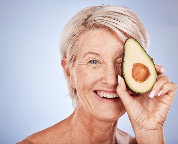 Gesichtspflege und Avocado mit einer älteren Frau im Studio auf grauem Hintergrund, um Anti-Aging-Antioxidantien zu fördern Porträtkosmetik und natürliche Behandlung mit einer reifen Frau, die für Wellness posiert