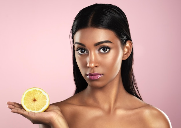 Gesichtspflege und Frau mit Zitrone im Studio isoliert auf rosa Hintergrund Obst ernst und Porträt eines indischen weiblichen Modells mit Zitrusnahrung für gesunde Haut, Vitamin C und Detox-Diät für die Ernährung