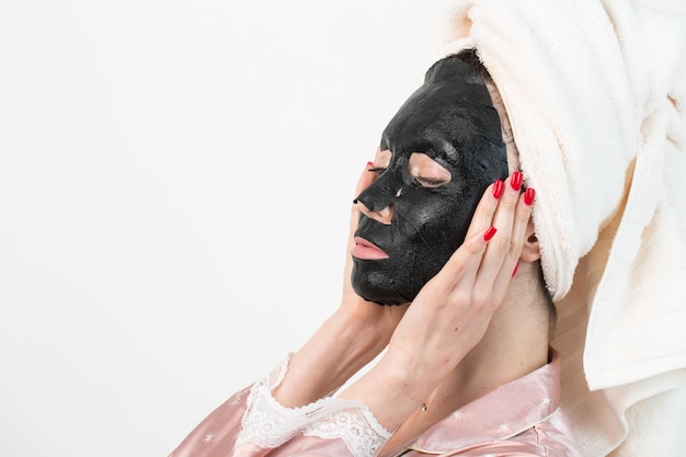 Gesichtspflege und Schönheitsbehandlungen Frau mit einer feuchtigkeitsspendenden Holzkohlemaske auf ihrem Gesicht isoliert auf weißem Hintergrund