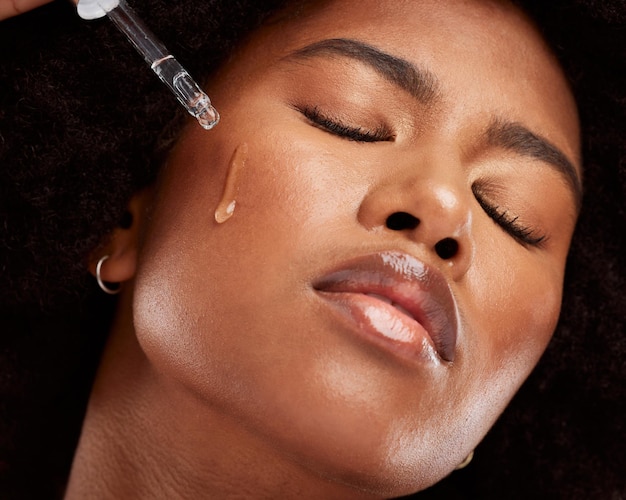 Gesichtspflege und schwarze Frau mit Pipettenserum für gesunde Haut Wellness-Schönheit und junges Model aus Nigeria mit Hyaluronöl-Tropfer für makellose Hautbefeuchtung oder Gesichtsbehandlung