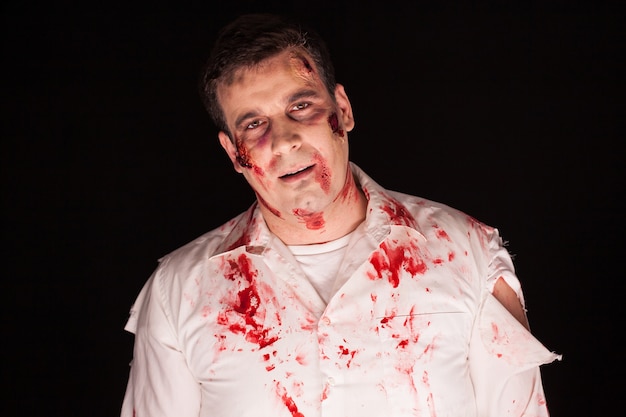 Gespenstischer Zombie mit blutigen Narben im Gesicht auf schwarzem Hintergrund. Böser Mann.